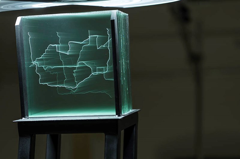 Nicole Khadivi,  Anatomy of an After, pt 2 Tjugonio platta glasskivor, graverade, metall, roterande ljus blandat med statiskt ljus, 2025. Originalstorlek 160x60x40cm. Foto: Pär Fredin